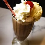 A dessert in a glass cup on a table, with Egg cream