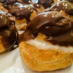 A close up of a Cream Puff on a plate, with Cream and Jasmine
