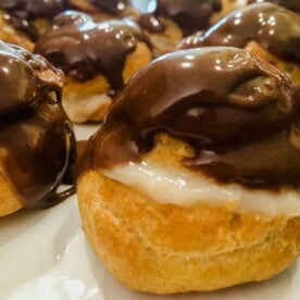 A close up of a Cream Puff on a plate, with Cream and Jasmine