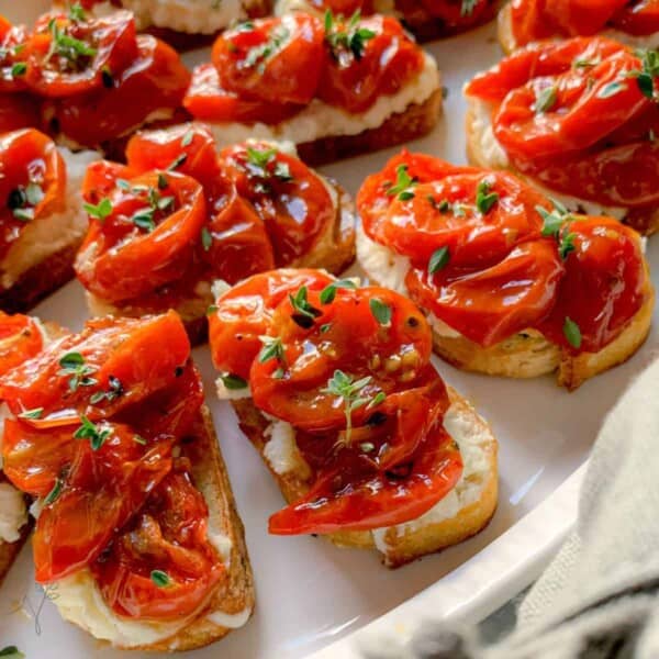 Lots of whipped feta appetizers on little toasts with roasted tomatoes on top.