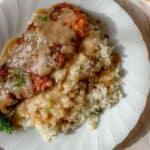A dinner plate heaped with rice and gravy topped with a crispy baked chicken cutlet.