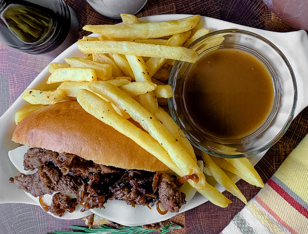 A sandwich and fries on a plate, with French dip and Roast beef