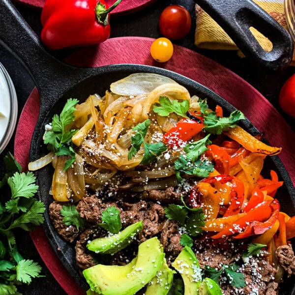 sizzling iron pan of shaved beef fajitas