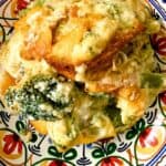 Cheesy cheddar broccoli casserole with melted cheese on top, served on a colorful patterned plate.