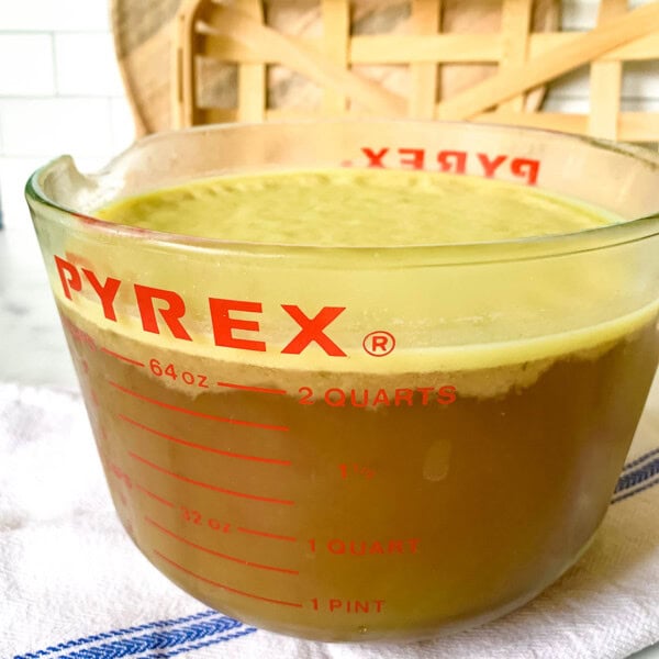 a glass measuring cup filled with ham stock