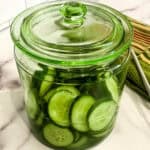 green glass jar filled with 3 Ingredient Charleston Flash Pickles sitting on a white counter with a lid