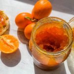 A jar of marmalade sitting on a table, with Kumquat and Marmalade