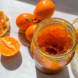 A jar of marmalade sitting on a table, with Kumquat and Marmalade
