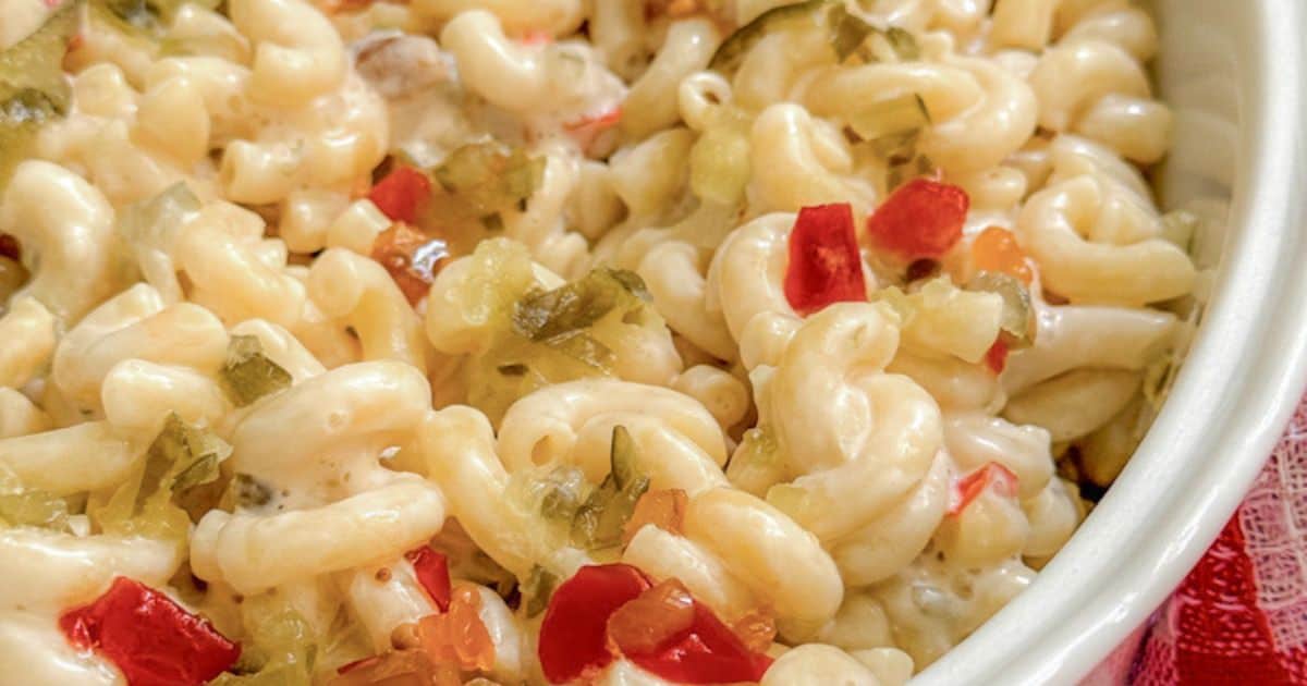 Close-up of creamy macaroni and cheese garnished with diced red and green bell peppers.