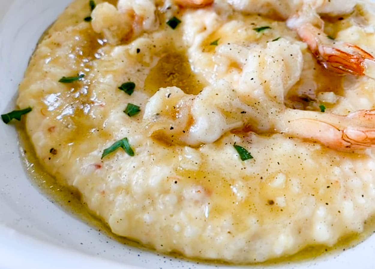 a white bowl with shrimp over grits