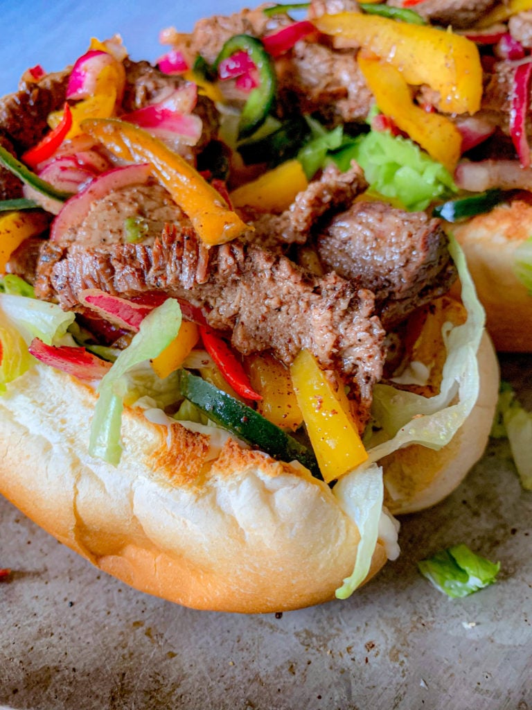 three steak hoagies on a broiler pan