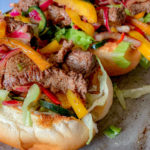 three steak hoagies on a broiler pan