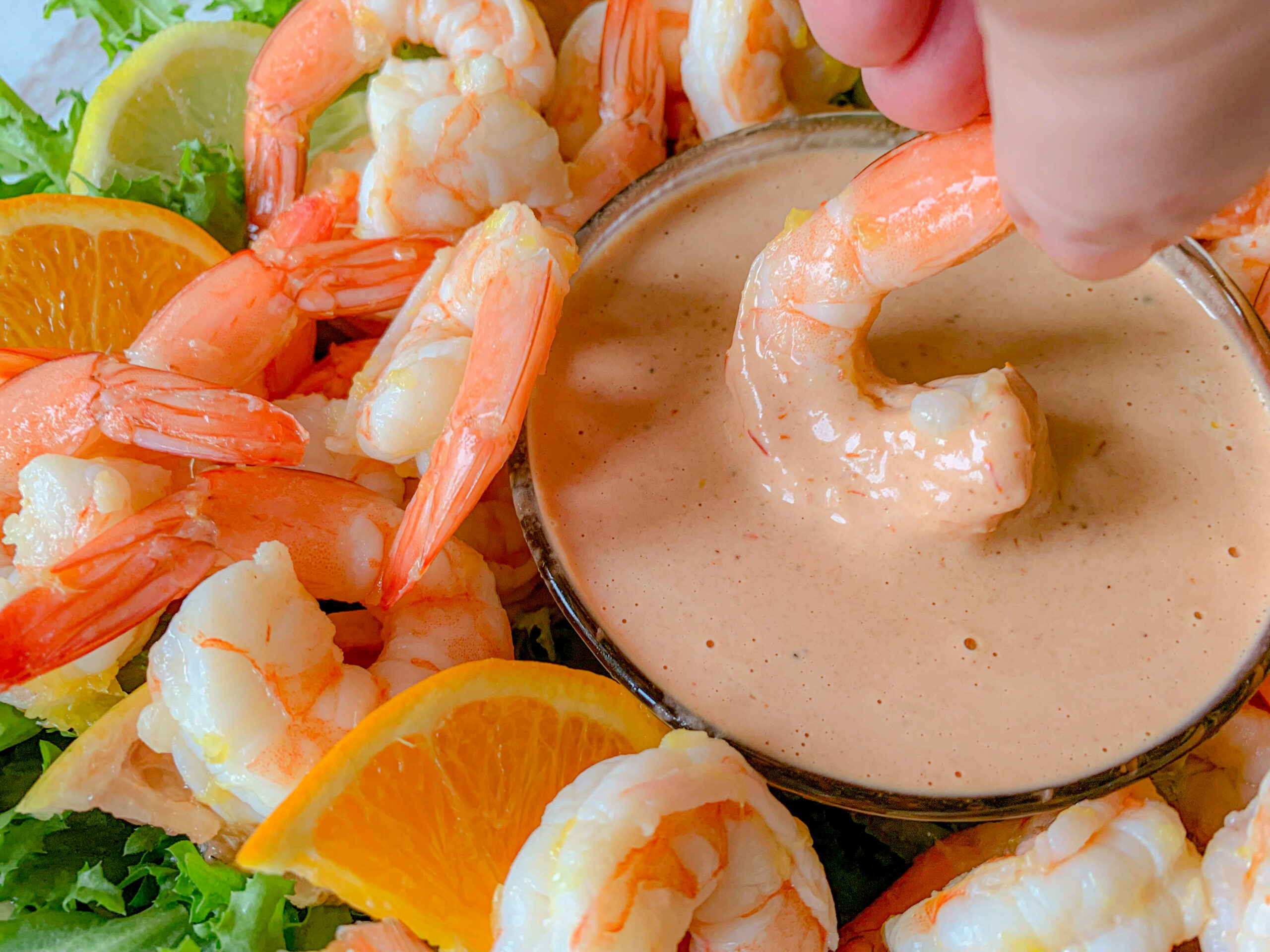 A woman dipping a shrimp into sauce.