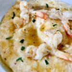 A white bowl with Honey Garlic Butter Shrimp over Pimento Cheese Grits.