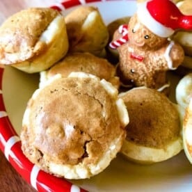 A porcelain Christmas serving bowl with a gingerbread man filled with Pecan Tassies cookies.