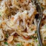 A creamy turkey tetrazzini garnished with chopped herbs and topped with breadcrumbs, with a partially visible metal fork in the dish.