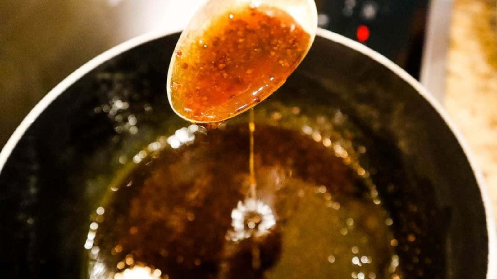 A spoonful of bourbon glaze dripping back into a hot pan.
