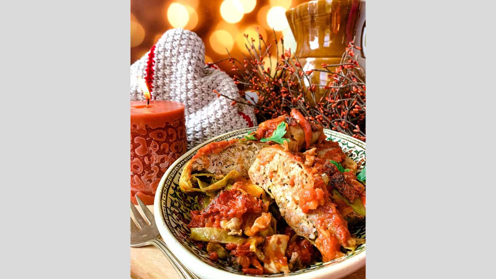 Stuffed cabbage rolls in a serving dish with sauce.