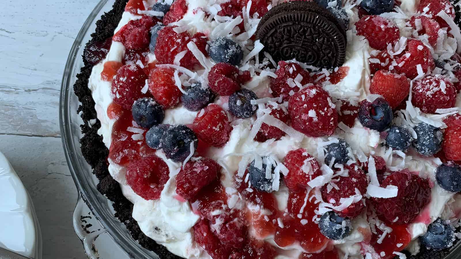 A berry pie with lots of whipped cream and OREO cookies.