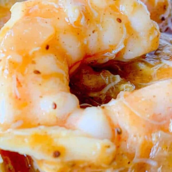 Close-up of cooked shrimp covered in a thick sauce with visible herbs and spices.