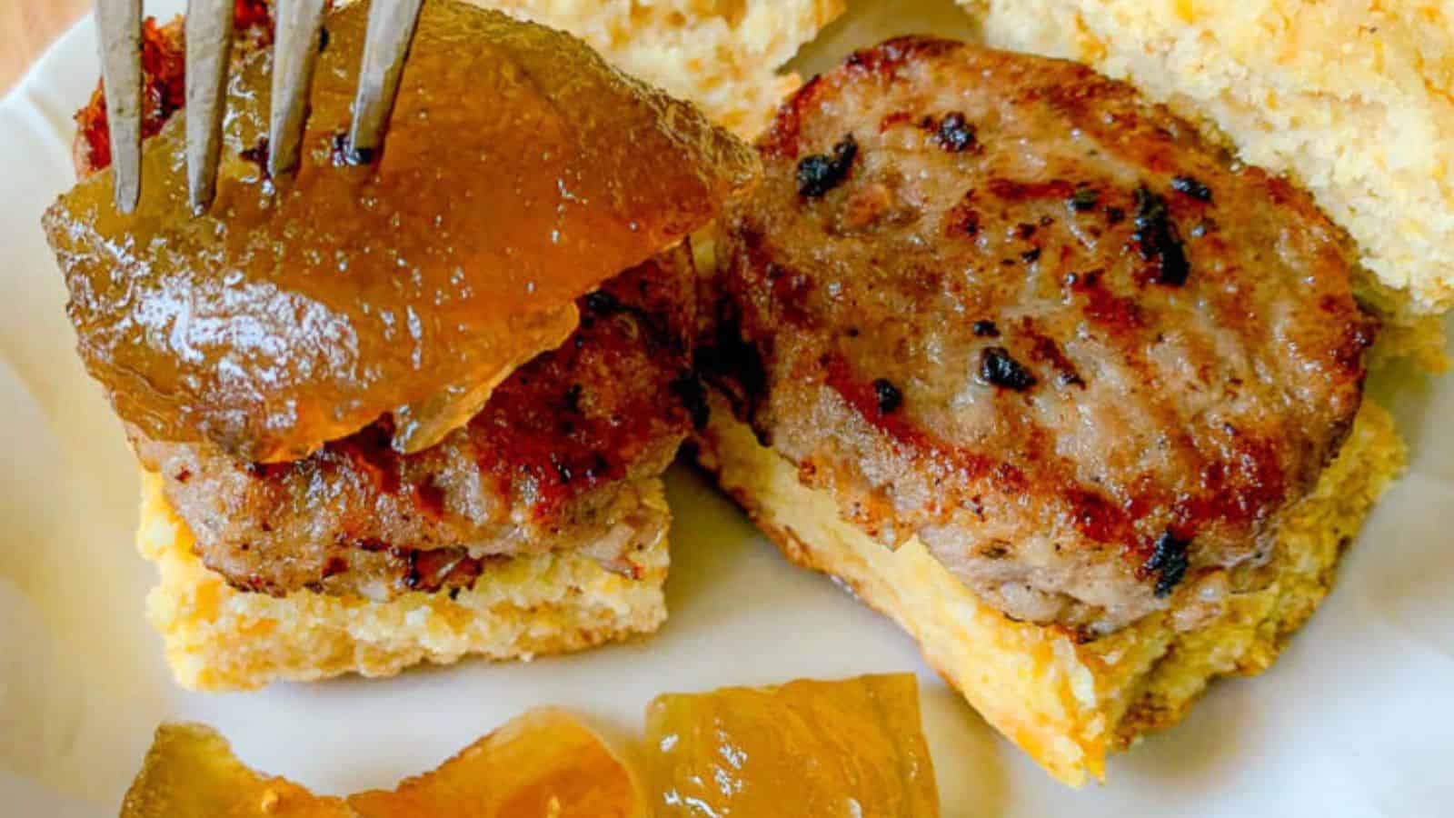 Two biscuits with sausage patties and preserves.