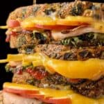 Stacks of melty grilled cheese sandwiches on a cutting board.