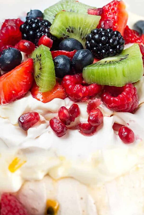 A pavlova dessert with fresh fruit and cream on the top.