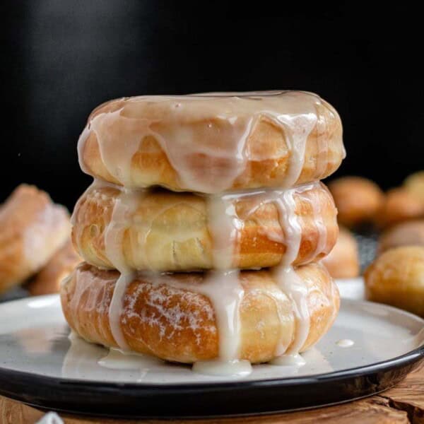 Three stacked donuts with icing dripping down.