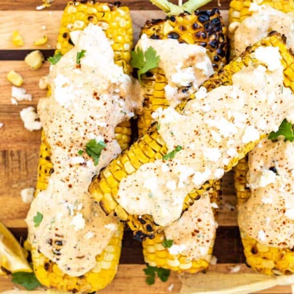 Grilled corn coated in white sauce and crumbled white cheese.