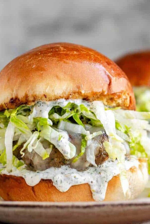 A burger with shredded lettuce and dripping sauce.