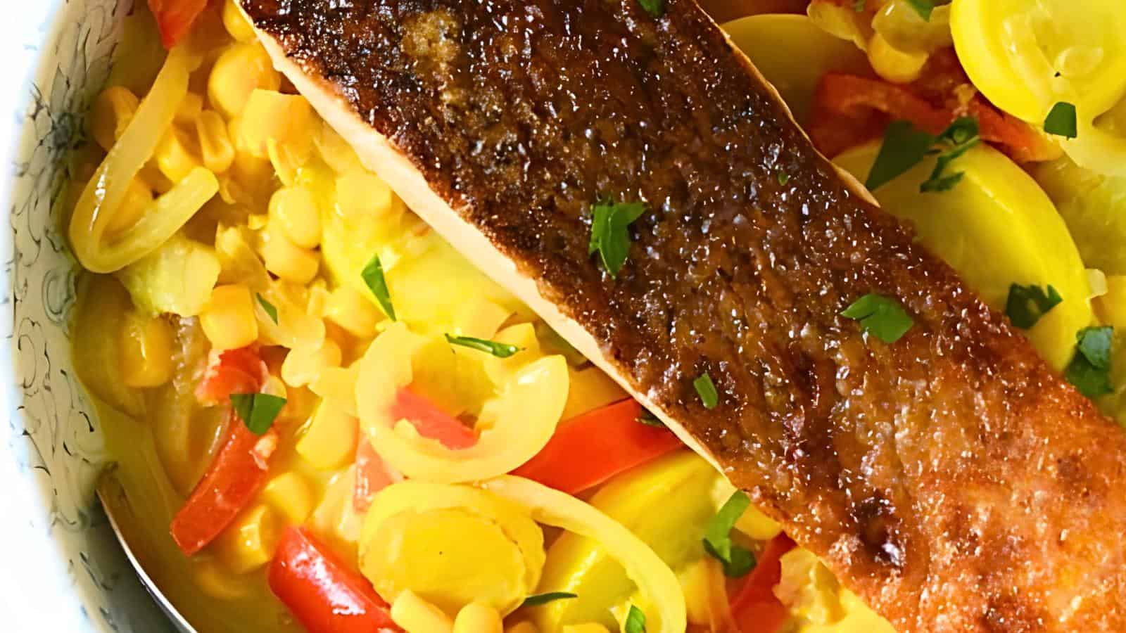 A cooked salmon fillet on a bed of sautéed corn, bell peppers, and onions, garnished with chopped herbs.