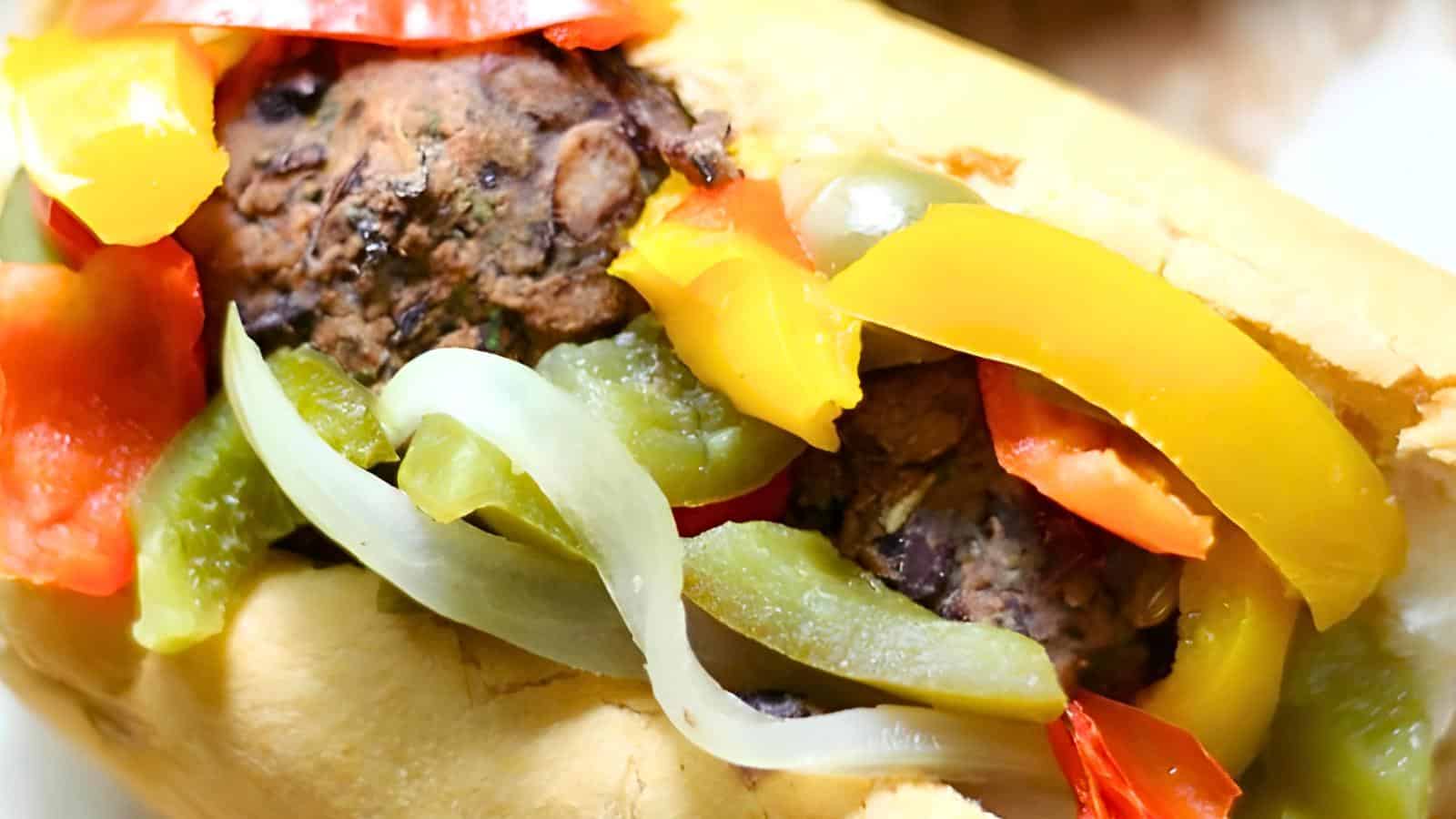 A sandwich filled with sausage and colorful bell pepper slices on a crusty roll.