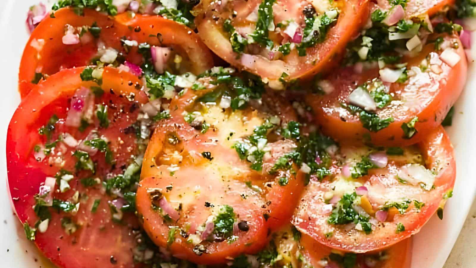 Tomato slices topped with chopped herbs, minced onions, and seasoning.