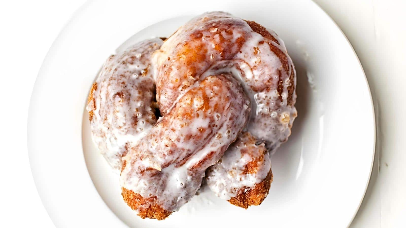 A glazed donut roll with icing on a white plate.