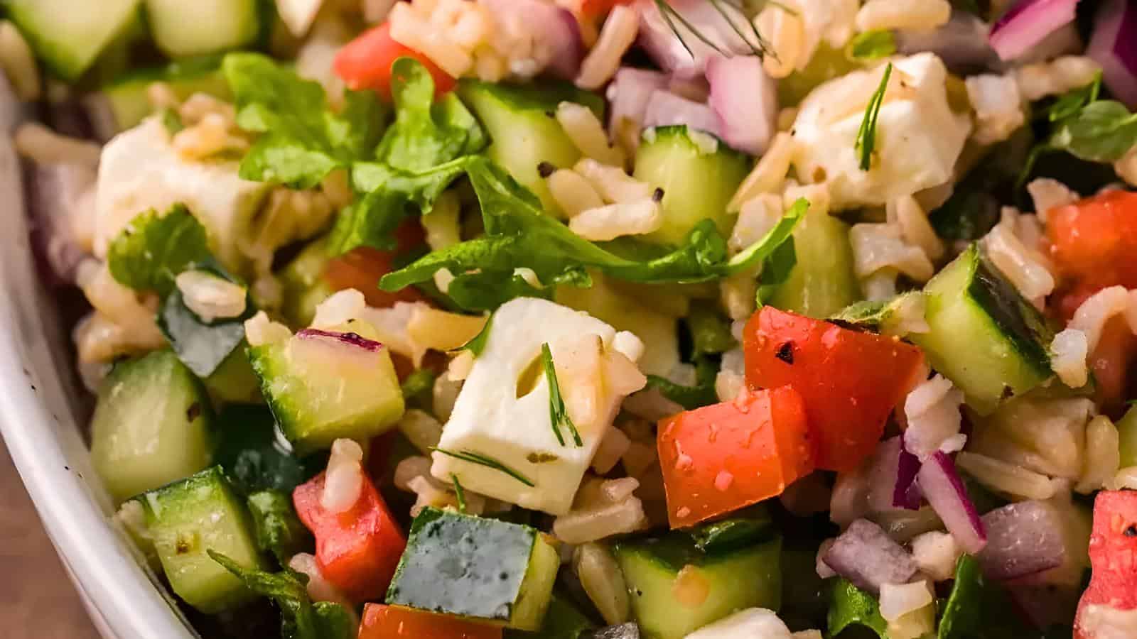 Diced cucumbers, red bell peppers, purple onions, feta cheese chunks, and herbs.