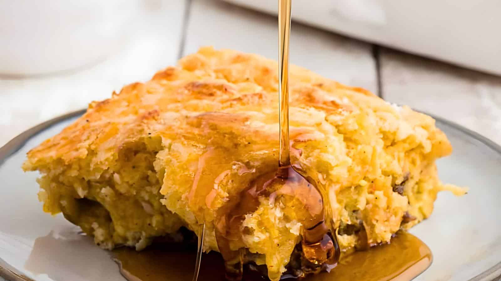 A plate with a piece of bisquick and syrup being poured over it.