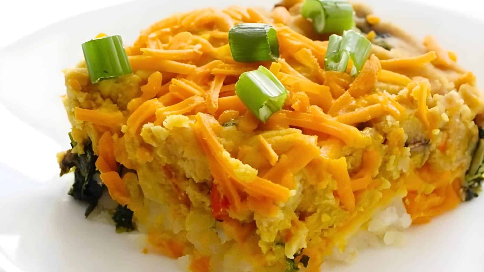 A layer of mashed vegetables topped with shredded cheese and garnished with chopped green onions.