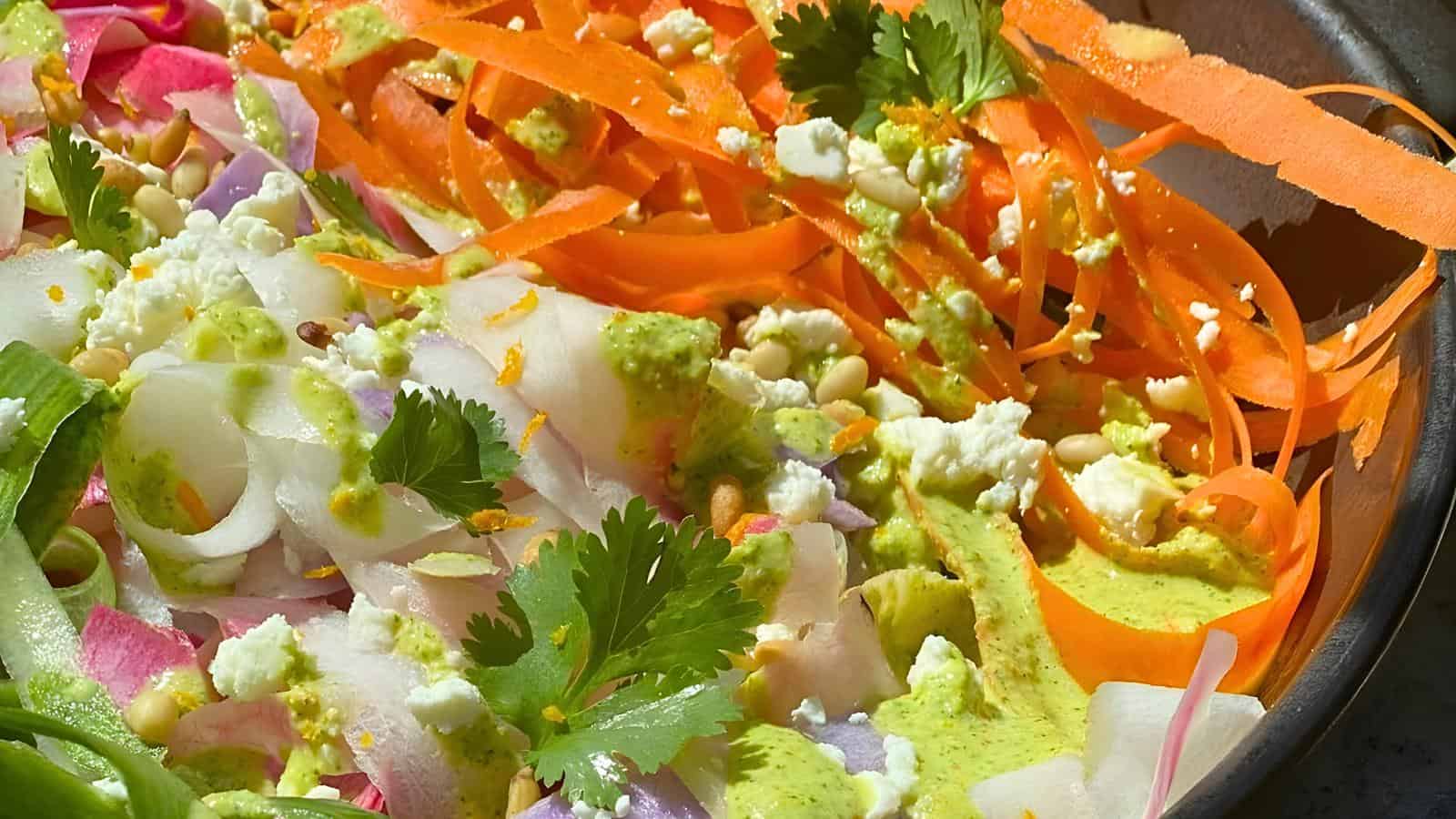 Shredded carrots, onions, cilantro, feta cheese, pine nuts, and a green dressing.
