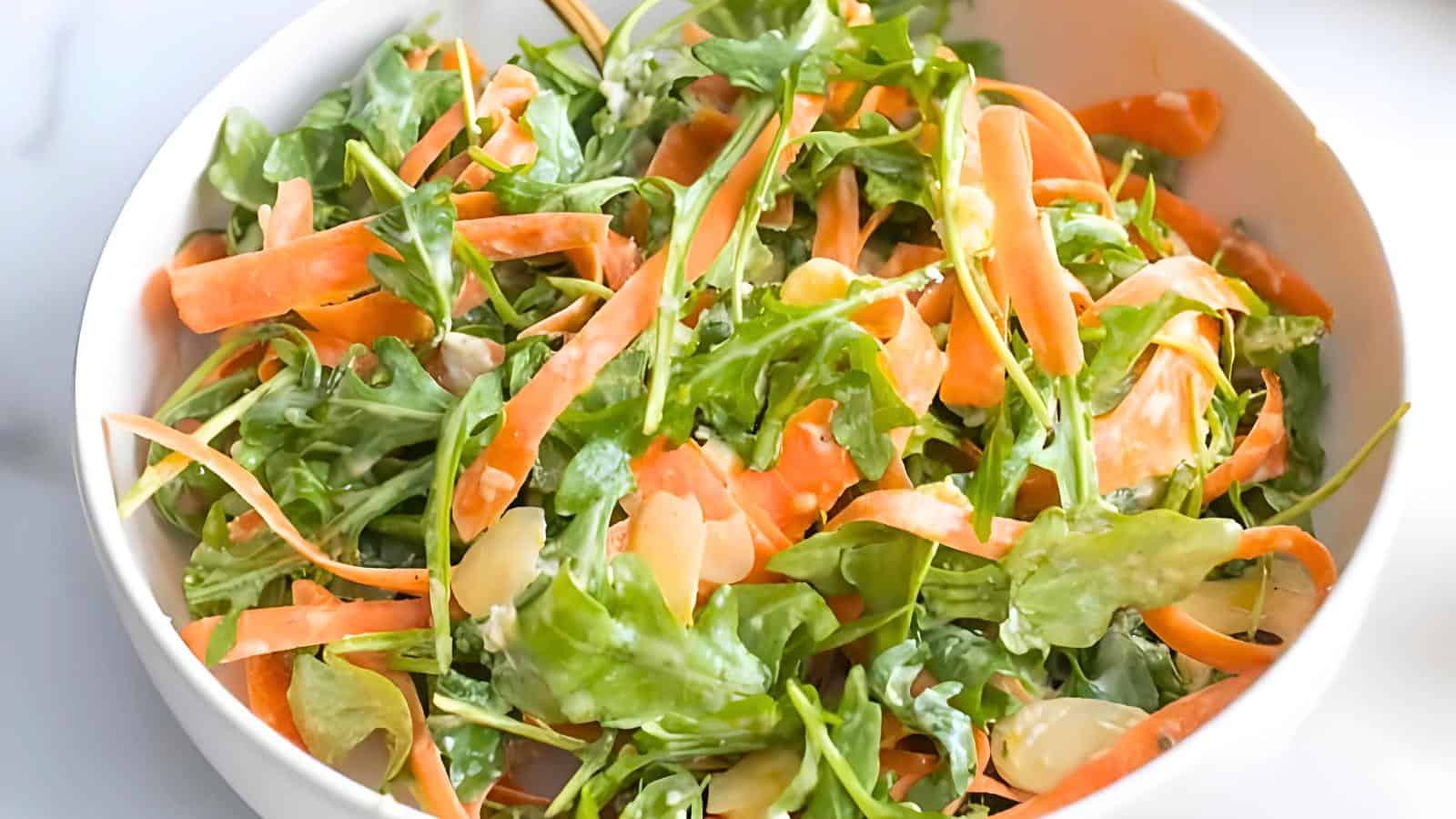 A bowl with leafy greens, sliced carrots, and a light dressing.