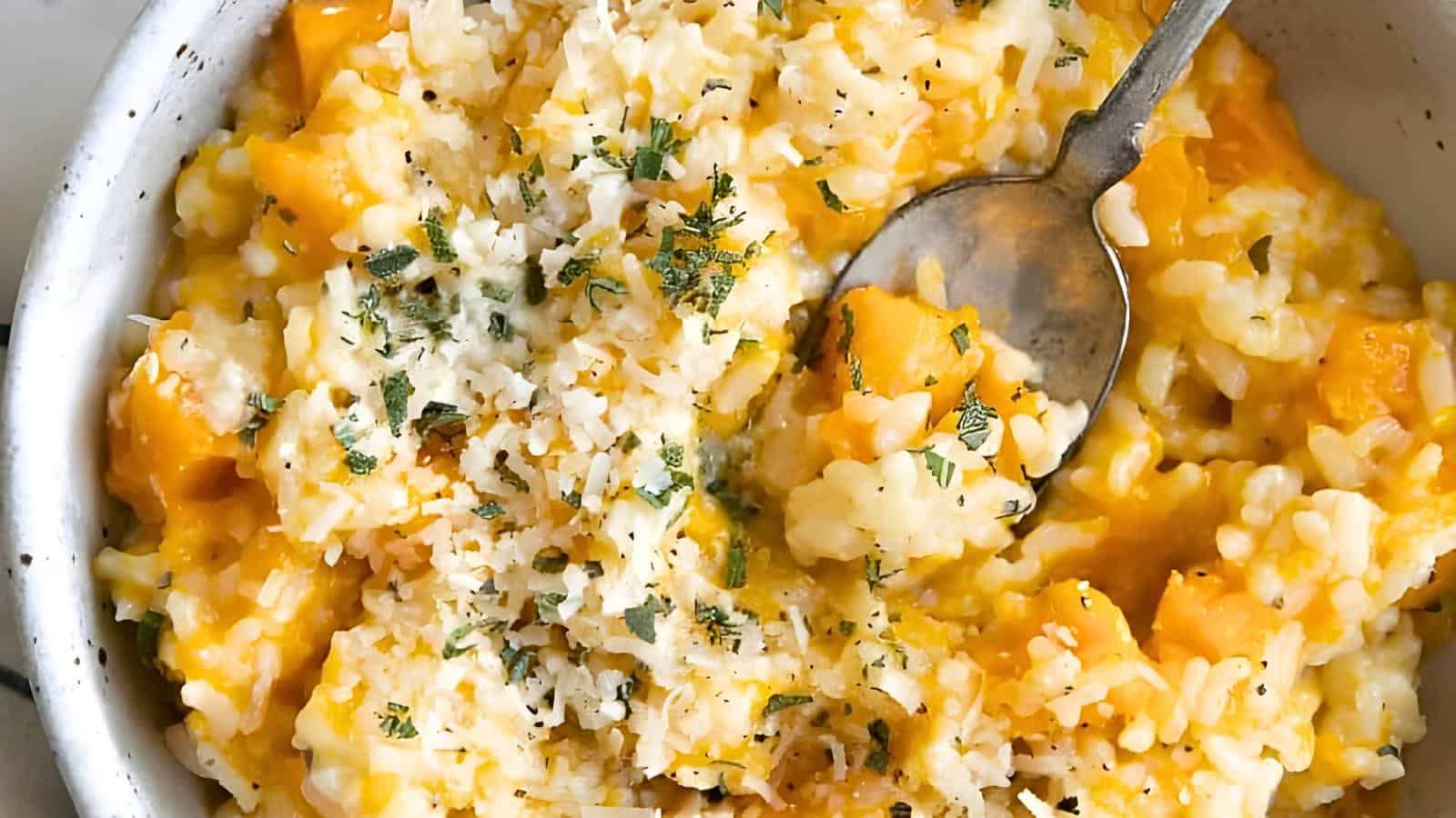 A bowl of creamy risotto topped with chopped herbs and grated cheese, with a spoon partially submerged.