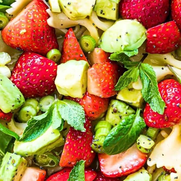 Bowtie pasta, sliced strawberries, avocado chunks, green peas, and mint leaves.