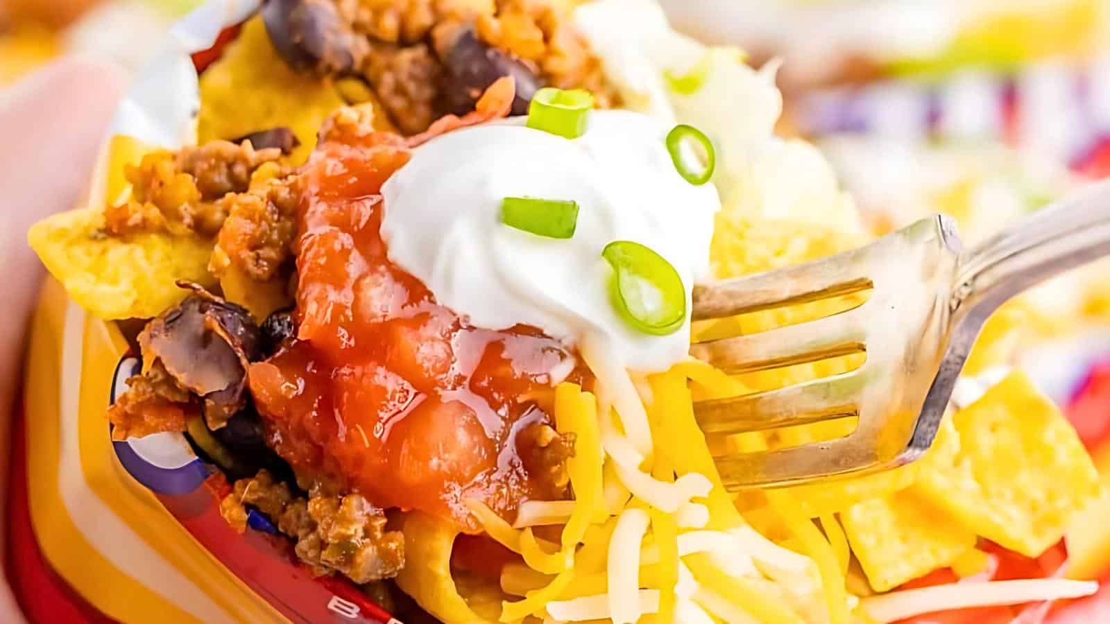 Tacos with ground beef, black beans, melted cheese, salsa, sour cream, and green onions.