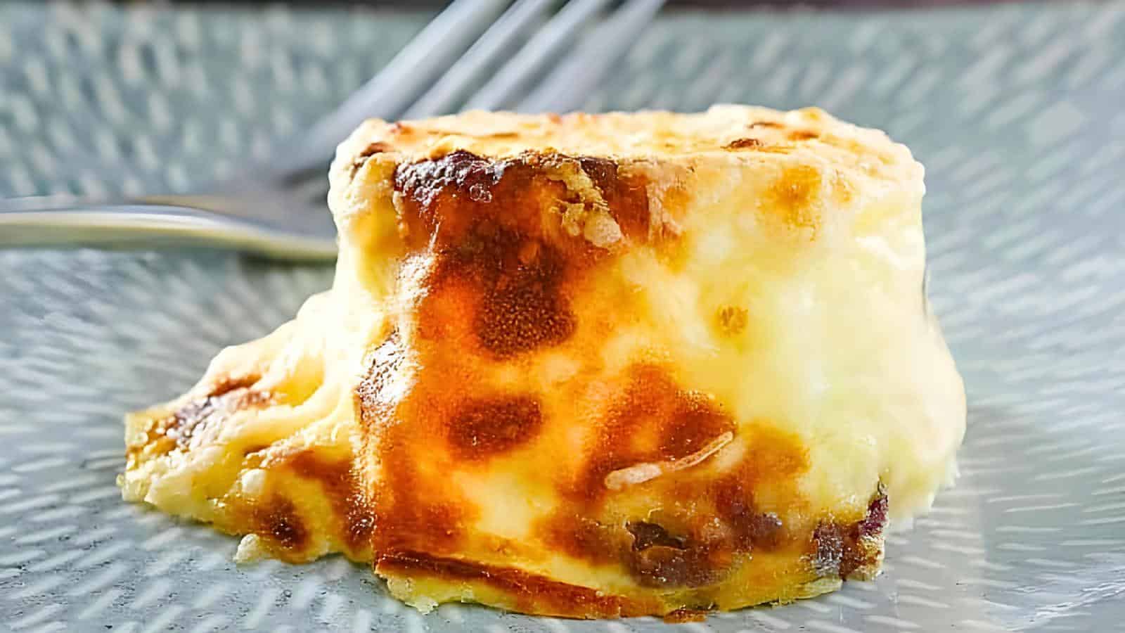 A piece of egg bites bacon with a fork in the background.