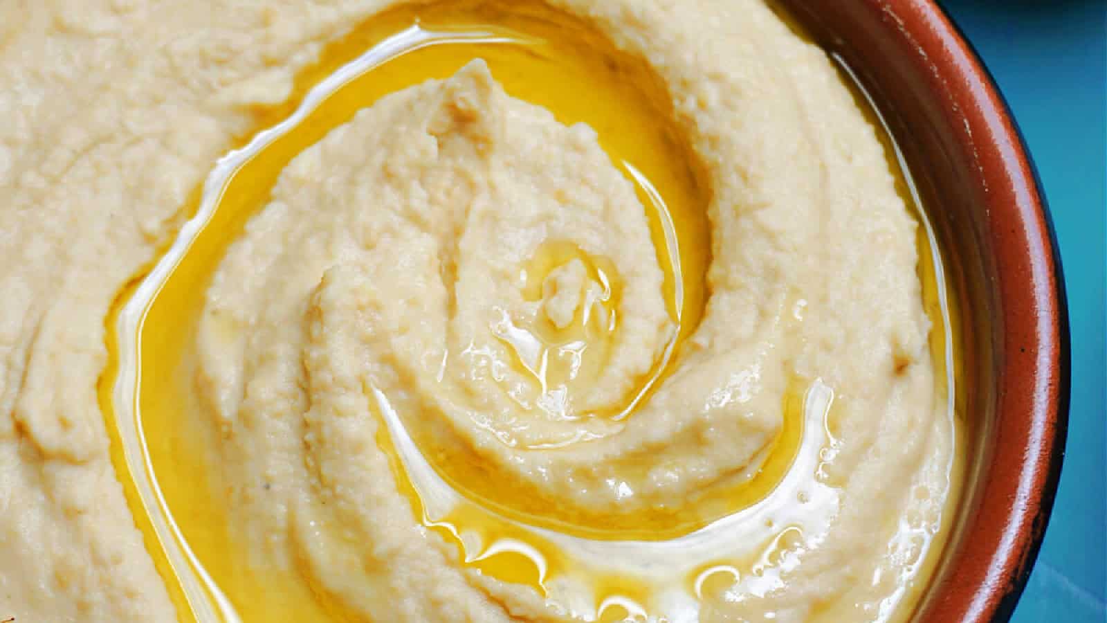 A ramekin with hummus and olive oil drizzled on top.