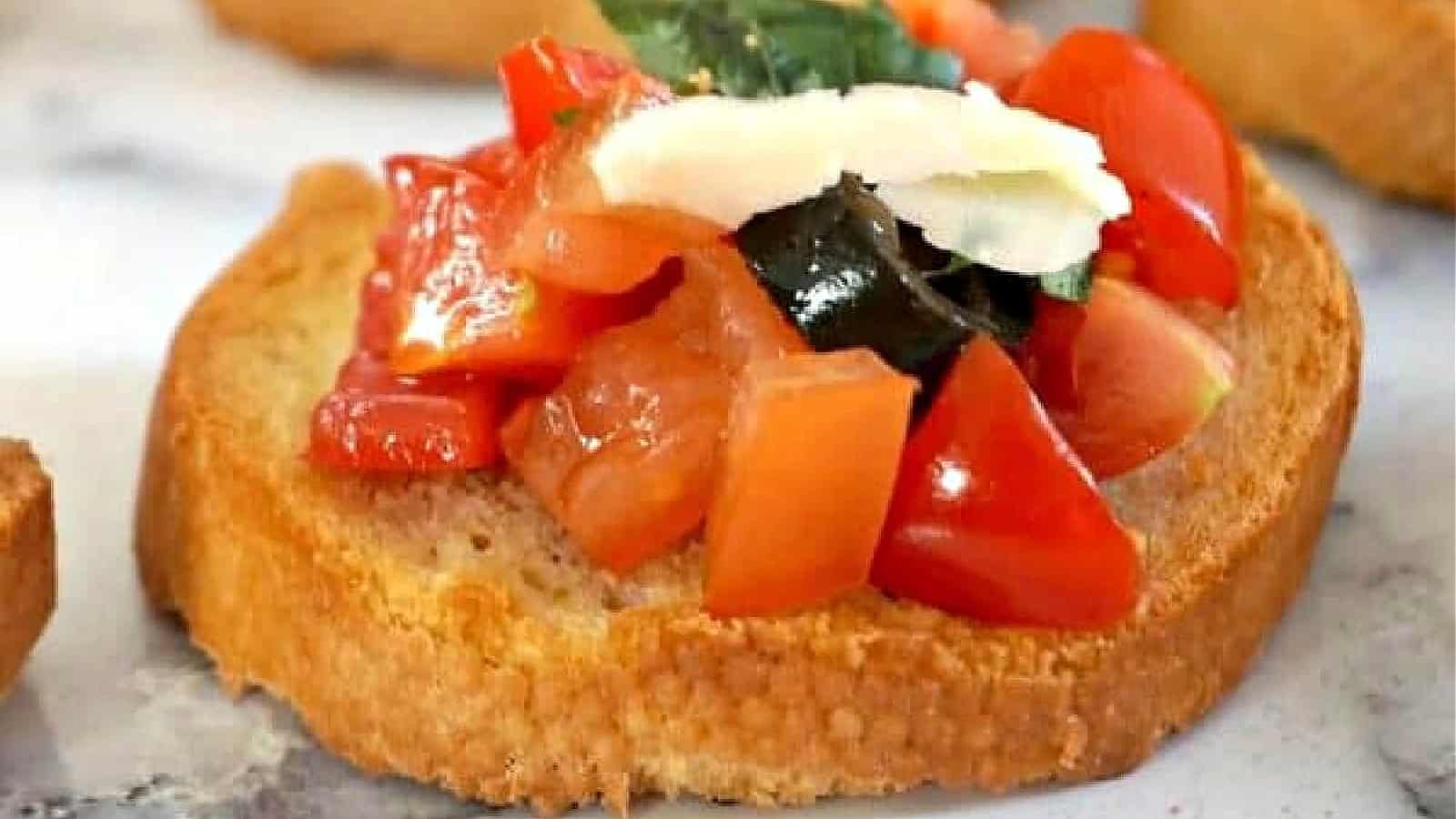 A slice of bread topped with tomatoes olives and cheese.