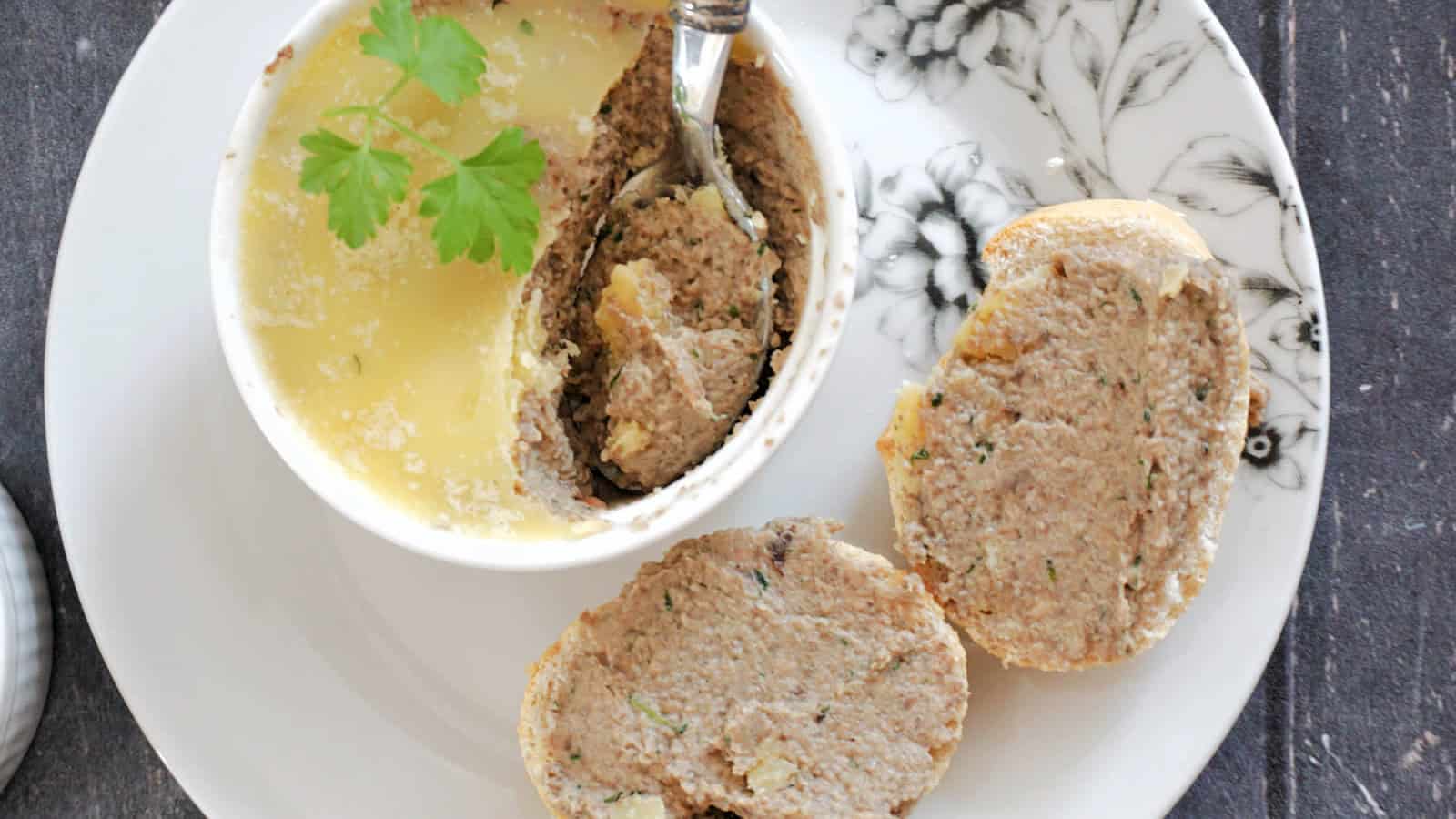 A ramekin with mushroom pate and 2 slices of bread spread with pate.