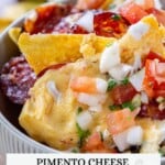 A bowl of pimento cheese nachos topped with chopped tomatoes, onions, and herbs. Text overlay: "Pimento Cheese Southern Nachos.