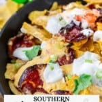 Pimento cheese nachos in a skillet, topped with pepperoni slices, sour cream, diced green onions, and chopped tomatoes.