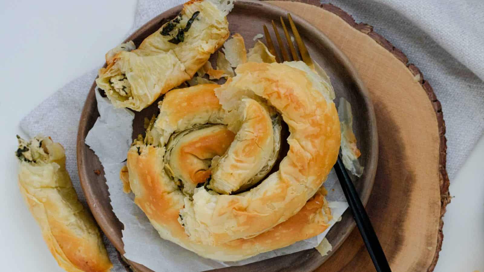 A large pastry swirl on a plate beside a fork.