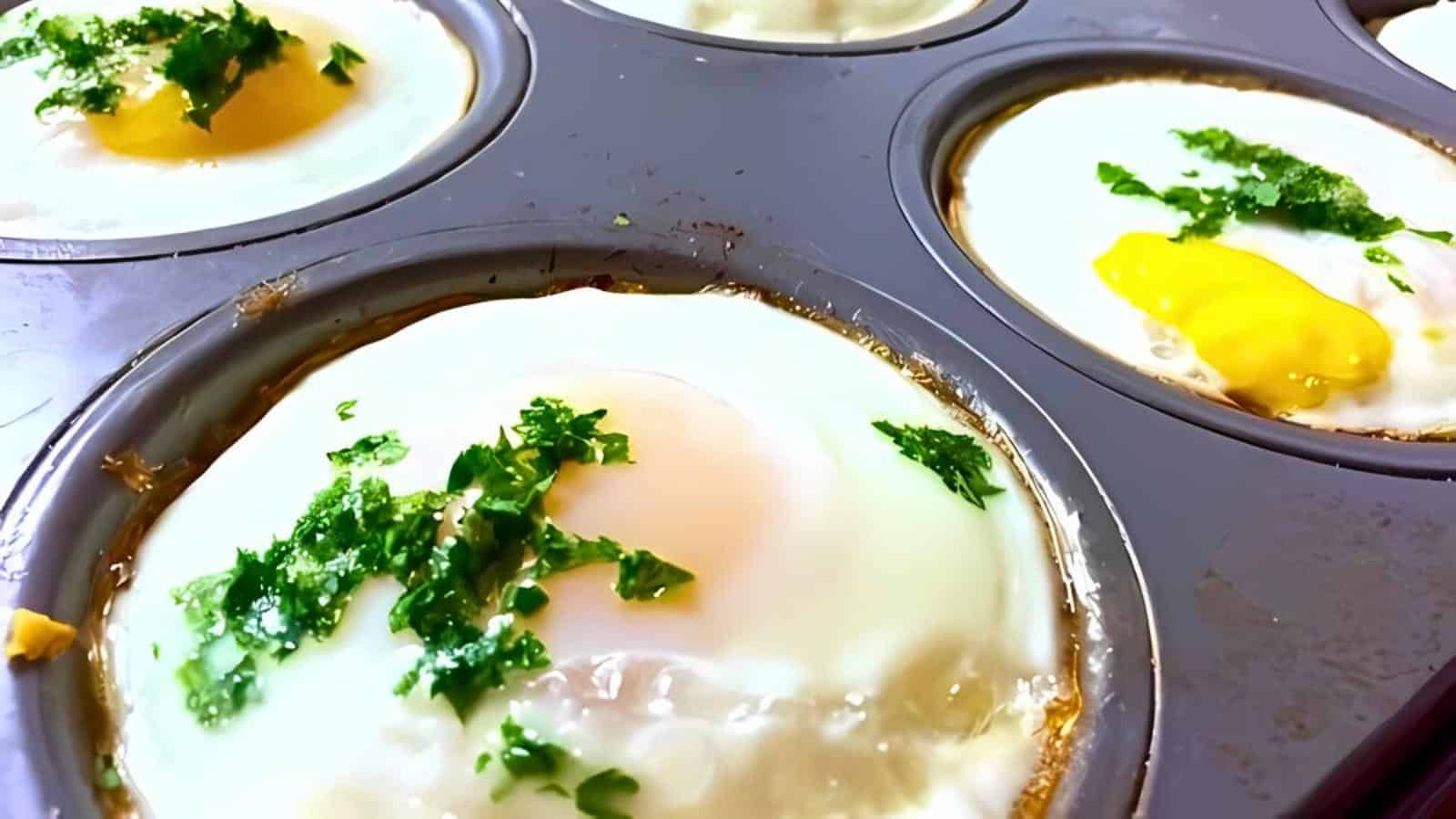 Eggs baked in a muffin tin, topped with chopped herbs, are shown. The eggs are cooked with firm whites and soft yolks, with a garnish of green herbs adding a fresh touch.